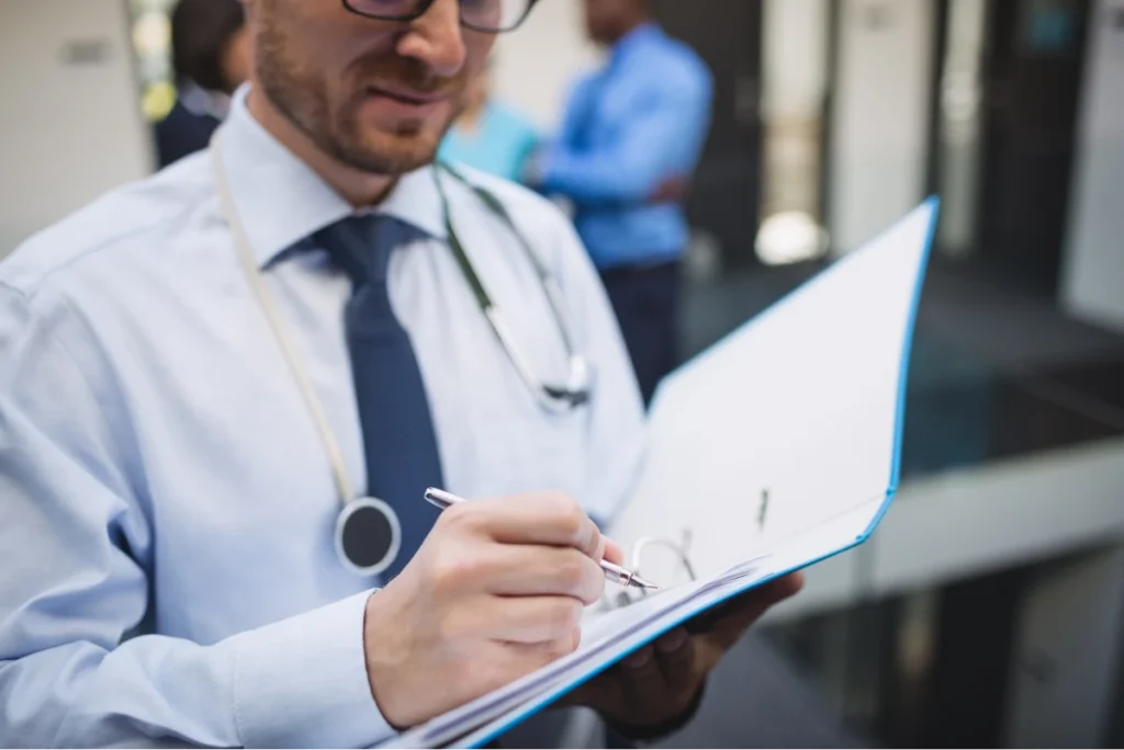 What Is Rheumatology? 4 Doctor writing notes on a clipboard, wearing a stethoscope around the neck.