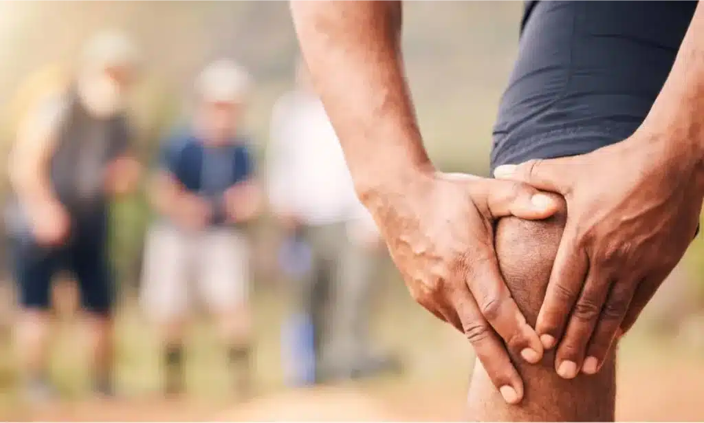 Recognizing the Common Symptoms of Arthritis 9 Person holding their knee in pain outdoors.